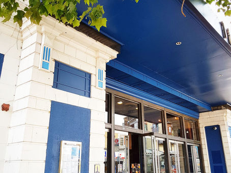 The blue and white front of the former Capitol cinema in Forest Hill, now a pub, with tree leaves overhead