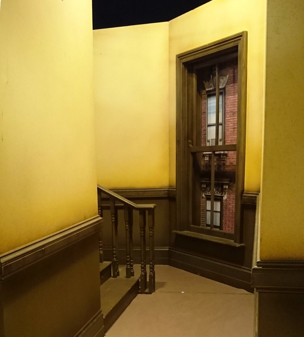 A narrow panelled staircase with a dark wood banister.