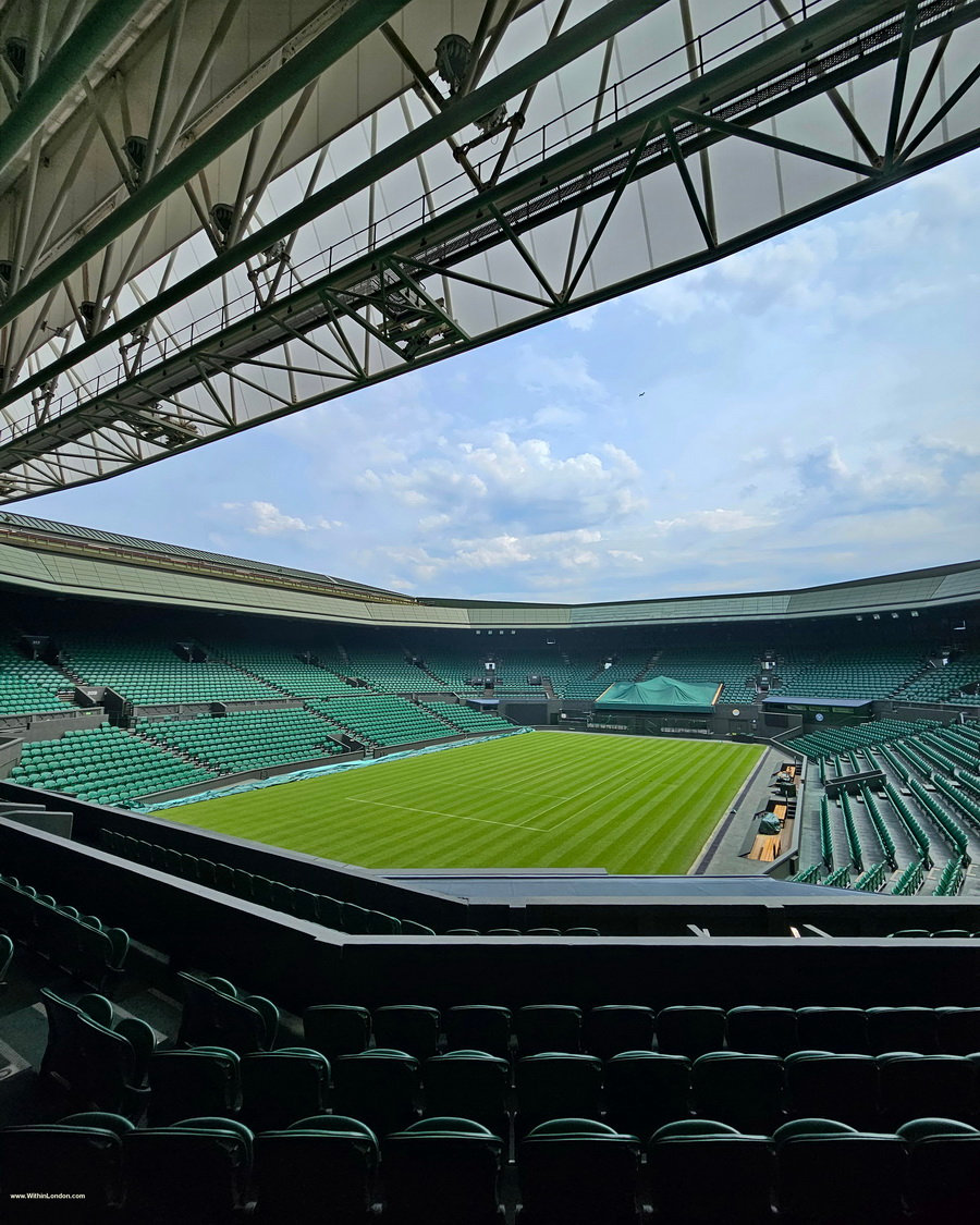 View down into an empty Centre Court from high in the stands, with the open roof structure above the grass