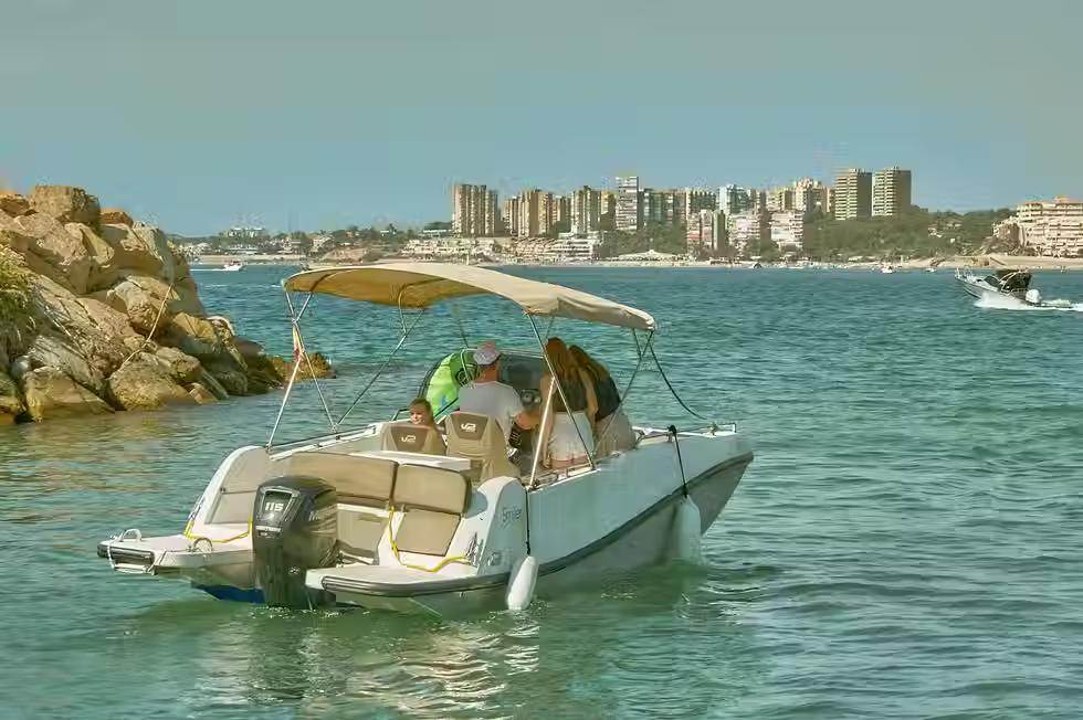 Pequeña embarcación a motor navegando cerca de la costa, sujeta a la nueva normativa de titulación obligatoria Real Decreto 1188/2025.