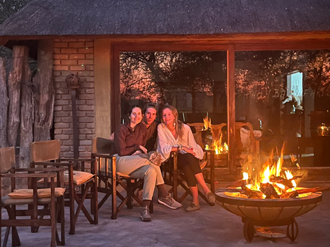 Guests sitting around fire in open boma at Phumba Safaris
