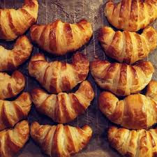 Petit-déjeuner maison en chambre d'hôtes avec viennoiseries artisanales, confitures maison et fruits frais de saison sur une table dressée.