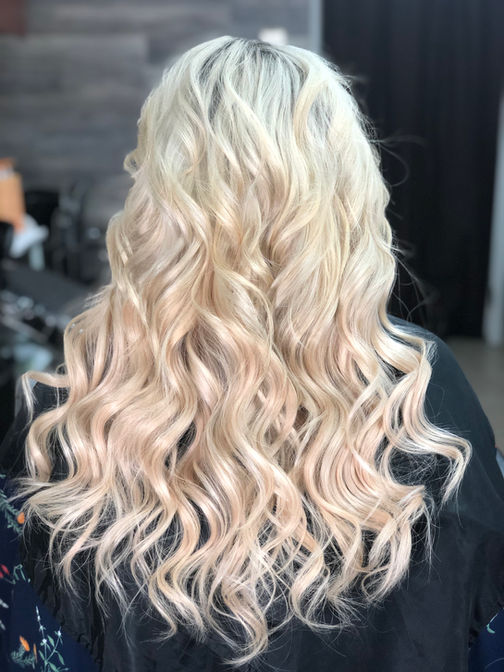 Client with a full blonde highlight transformation, complemented by hair extensions for added volume and length, creating a seamless and vibrant look