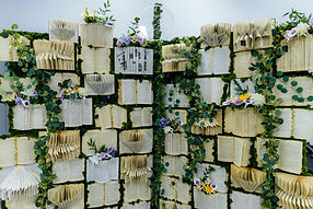 Book wall. A large portable photo backdrop wall with books attached to it. The books are open with folded pages, flowers and vines decorate the wall.
