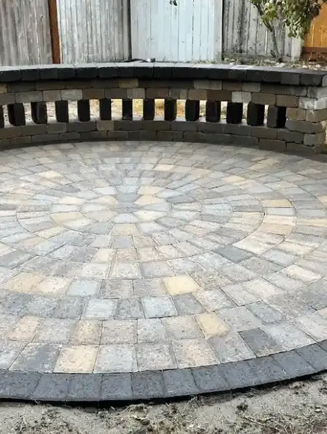 Circular paver patio with a curved seating wall designed for a custom outdoor fire pit installation.