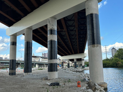 Series of bridge columns along a river reinforced with black carbon fiber wraps.