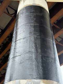 Close-up of concrete bridge column wrapped in carbon fiber showing tight, glossy surface finish.