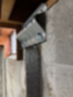 Simpson Strongtie URFP bracket fastening the foundation wall to the sill plate over a carbon fiber strap of SRS-600UNI
