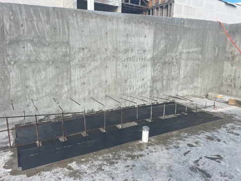 Post-tensioned slab reinforcement in progress, with carbon fiber reinforcement applied to the concrete surface and steel reinforcement bars installed for structural strengthening.