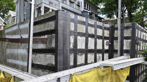 Retaining wall reinforced with a full carbon fiber grid pattern, including continuous wrap around the corner for added structural support