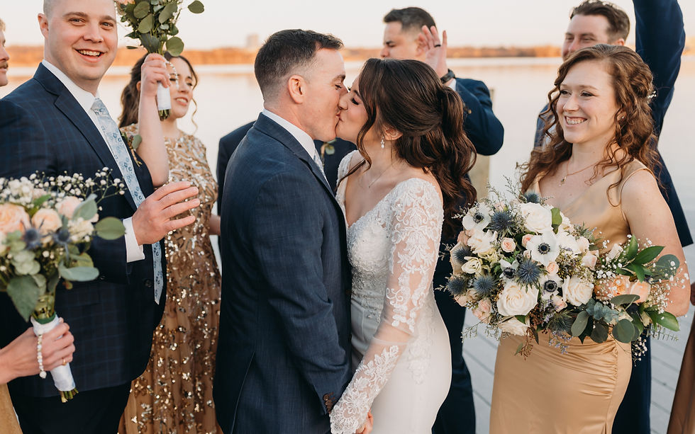 Couple kissing surrounded by their wedding party. Virgina wedding on a waterfront dock.