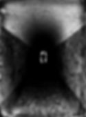 Fotografia em preto e branco de um túnel estreito e escuro, com paredes de pedra e teto curvo. Ao fundo, na pequena abertura iluminada da saída, vê-se a silhueta de uma pessoa em pé, recortada contra a luz, criando um contraste dramático entre sombra e claridade