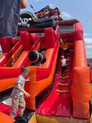 Dzieci zjeżdżają z dmuchanej zjeżdżalni w kształcie statku pirackiego