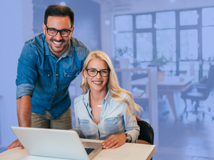 A man and woman are sitting at a laptop