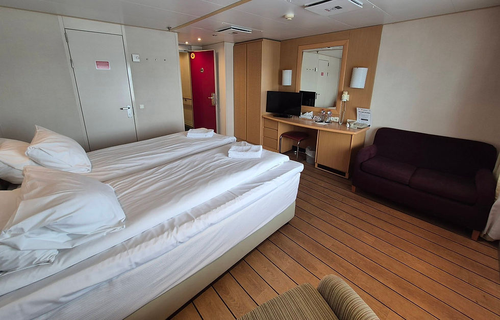 Tidy Hibernia Line ferry cabin with two white beds, desk and TV, burgundy door, sofa, and a Welcome on board sign near the mirror.