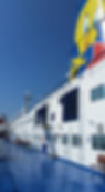 Moby Lines ship deck with blue floor, white walls, and a large cartoon yellow bird on the smokestack. Clear sky background. Passengers relaxing.
