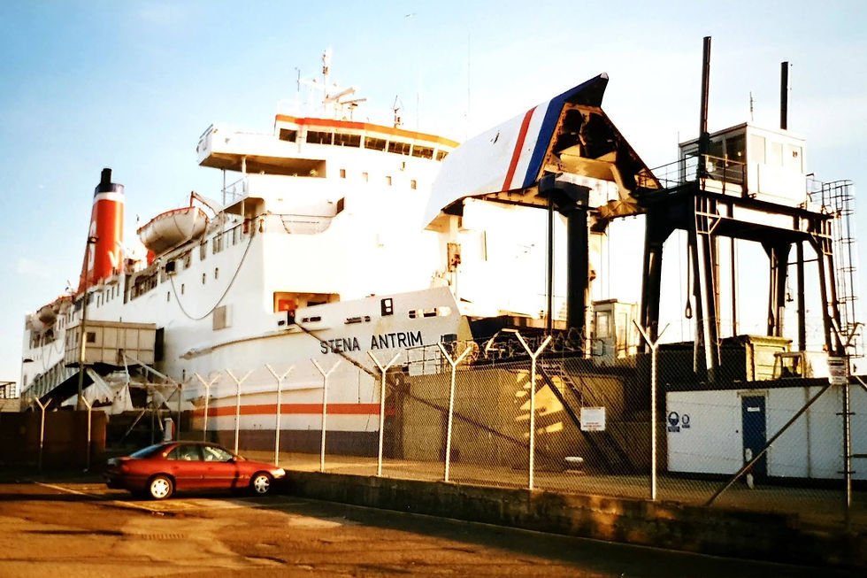 Docked ferry "Stena Antrim" in Newhaven UK with red, white, and blue stripes. Nearby, a red car is parked behind a fence under a clear sky.