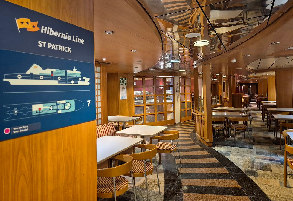 Empty Hibernia Line ship dining room with tables and chequered chairs; Hibernia Line St Patrick sign on wood wall and mirrored ceiling.