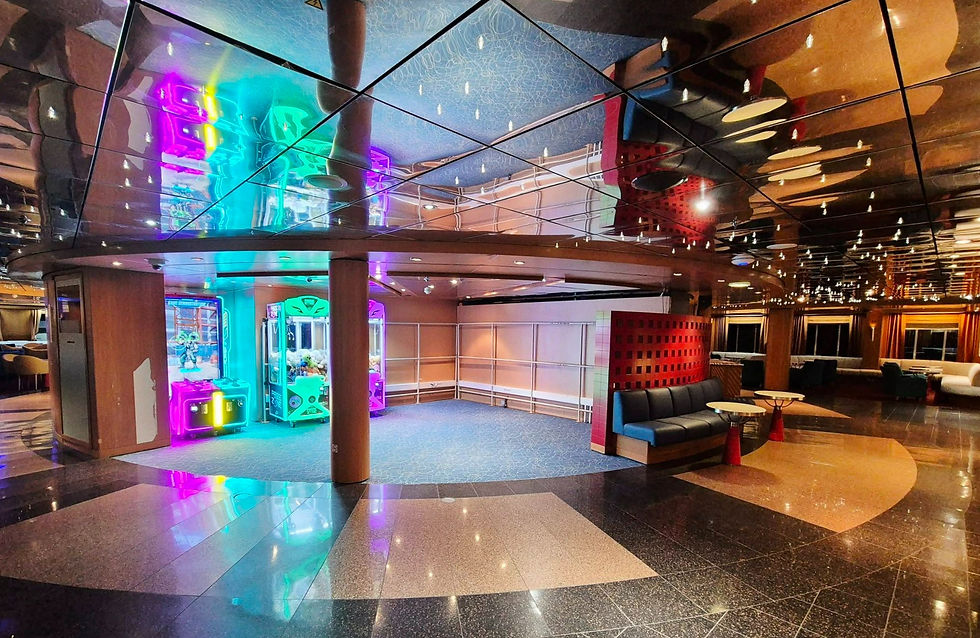 Empty Hibernia Line ferry lounge with neon claw machines, mirrored ceiling, and seating under warm lights.