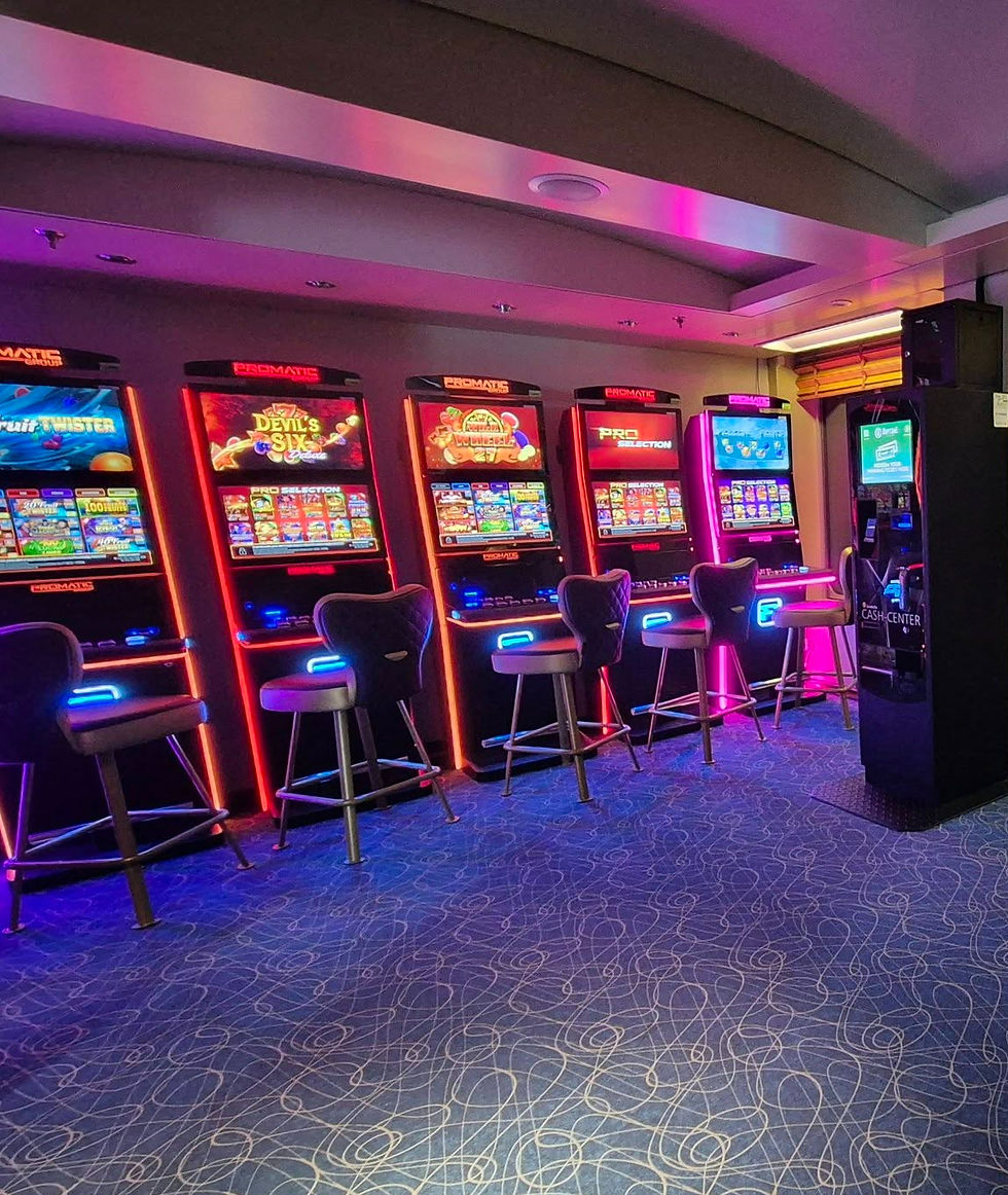 Empty casino row on Hibernia Line ferry with glowing slot machines and stools, neon pink and blue lights, patterned carpet, no players visible
