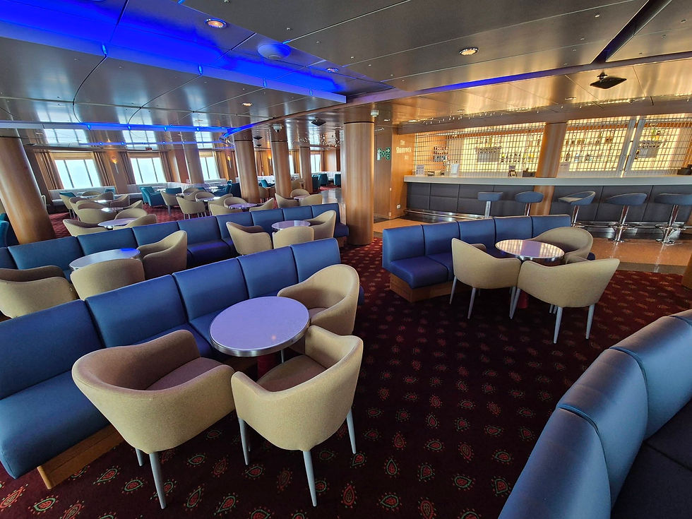 Empty Hibernia Line ferry lounge with blue-lit ceiling, beige chairs and navy sofas, and The Shamrock Bar counter.