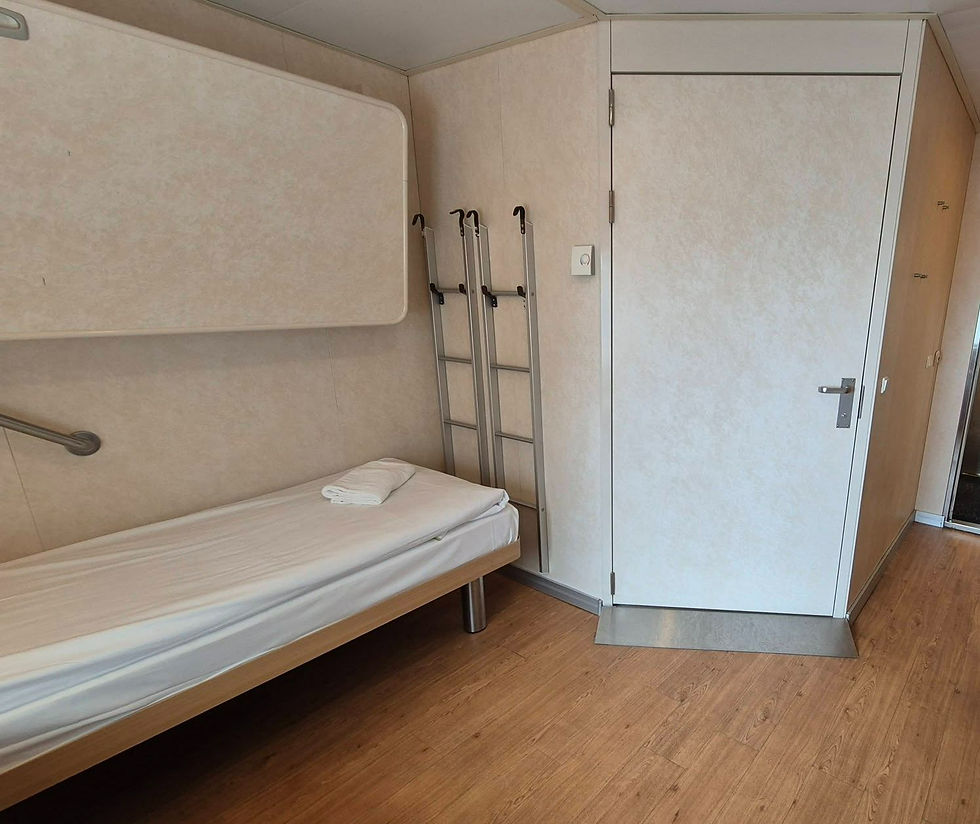 Hibernia Line ferry accessible bathroom for wheelchair, folded towel, wall rails, and a white door on wood floor, clean and quiet