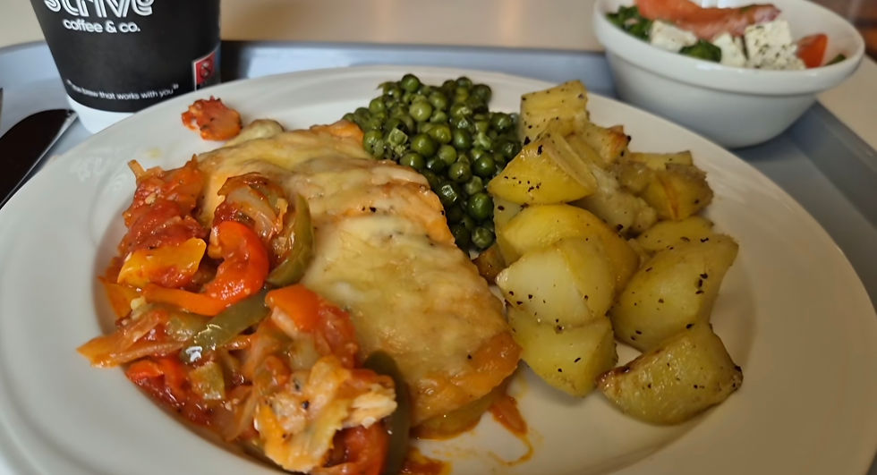 Cafeteria tray with baked fish or chicken, tomatoes and peppers, peas, roast potatoes, and a coffee cup.