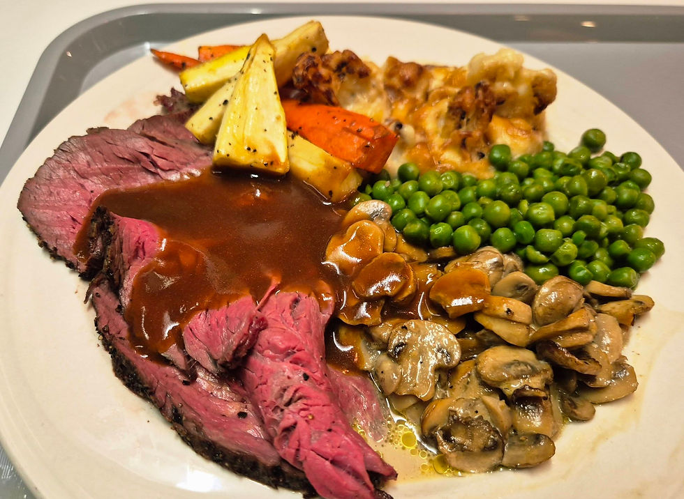 Plated roast beef with gravy, peas, mushrooms, roasted carrots and parsnips, and cauliflower cheese on a white plate from the Hibernia Line buffet