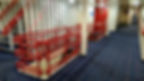 Interior with blue carpet and red railings around stairs. Patterned walls and doors visible, creating a clean, orderly ship-like setting.