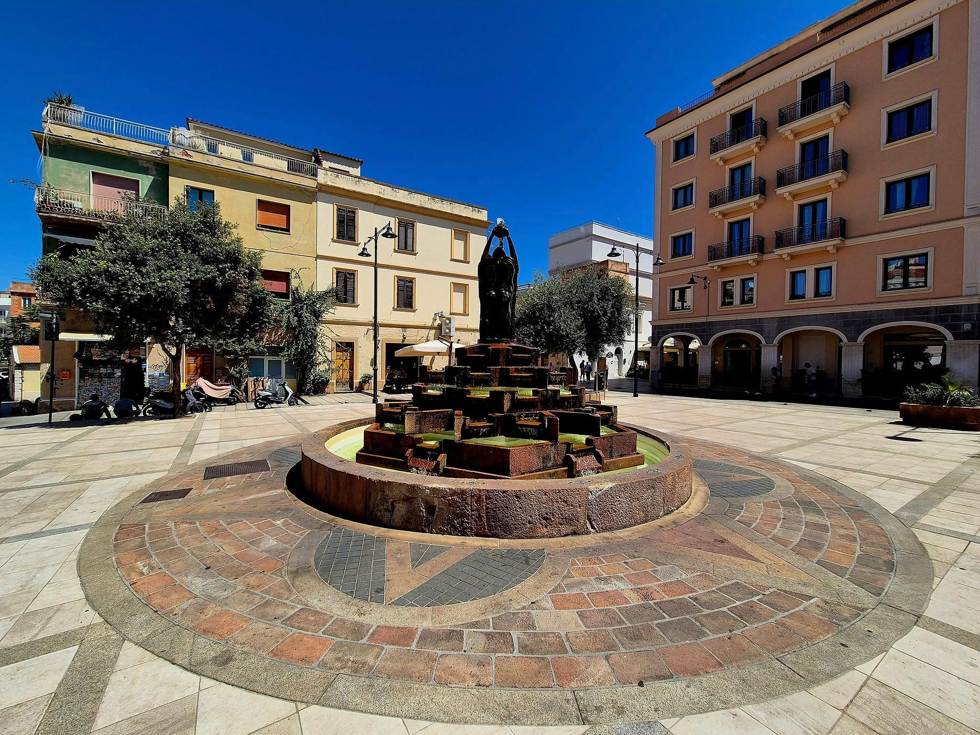 granite planter with decorative plants, traditional buildings under blue sky