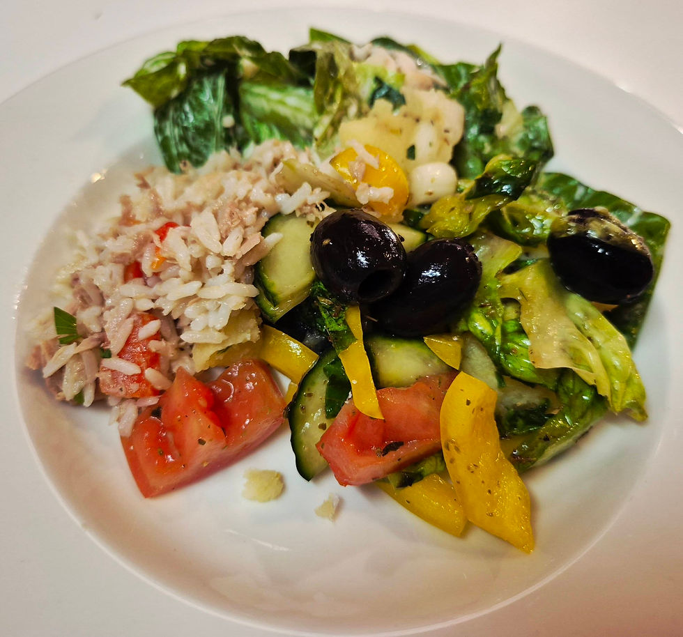 Plate of mixed salad on Hibernia Line ferry with rice and tuna, lettuce, tomatoes, cucumbers, yellow peppers, and black olives on a white plate
