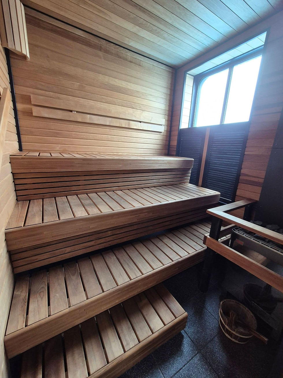Empty wooden sauna aboard a Hibernia Line ferry with tiered benches, slatted walls and bright window light, creating a warm, calm atmosphere.