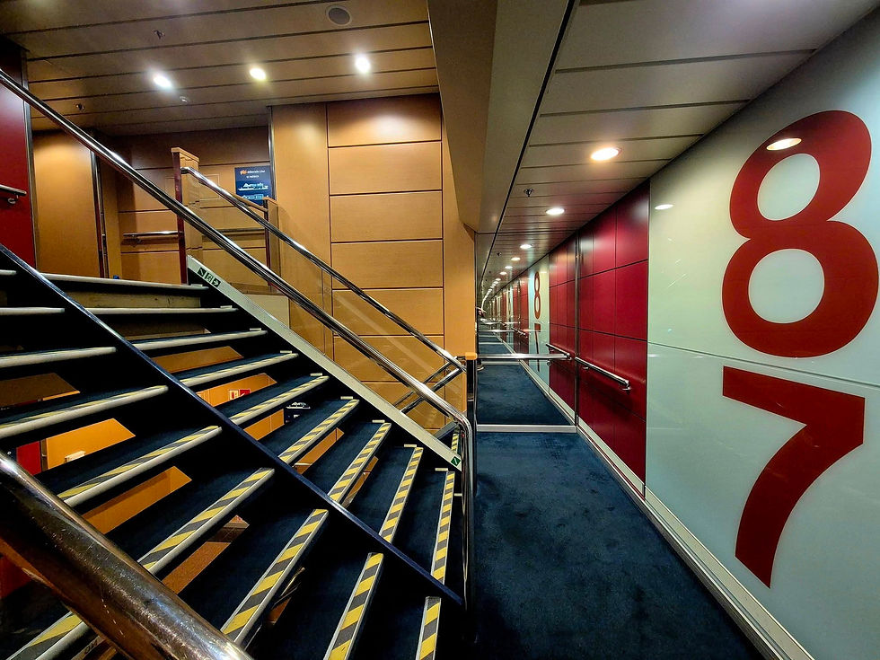 Hibernia Line ship stairwell corridor with blue carpet, metal rails, and large red 8 and 7 on white and red walls.