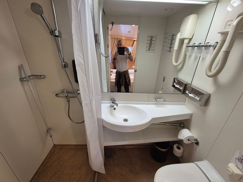 A2B via Sea taking a mirror selfie in a ferry bathroom with shower, sink, and beige-white fixtures.