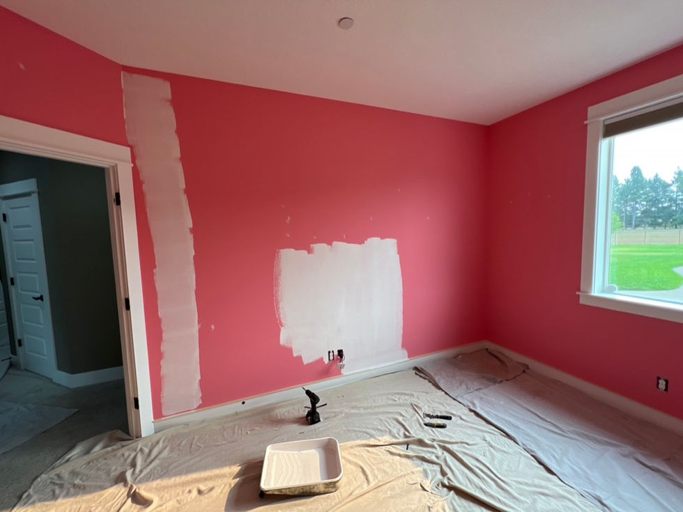 Professional interior painting in Tualatin showing white primer being applied over a bright orange wall