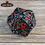 Thumbnail: Black metal twenty-sided die with red accents