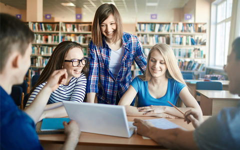 Five student studying in a library with a computer