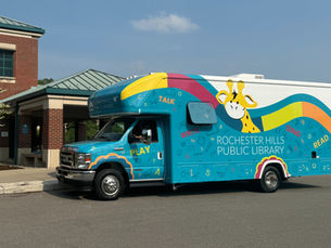 The new early literacy bus has Stretch the giraffe mascot on it along with hand drawn icons related to reading and playing.