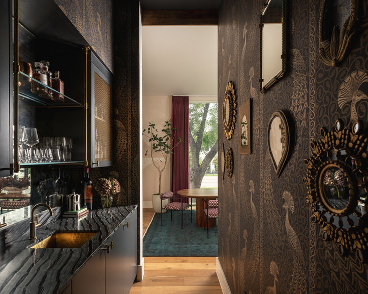 Moody hallway in the Timberline residence with a black lacquered home bar and collection of circular wall mirrors.