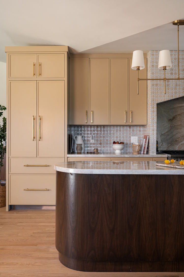 Curved dark wood kitchen island with Taj Mahal quartzite countertop and custom taupe cabinetry.
