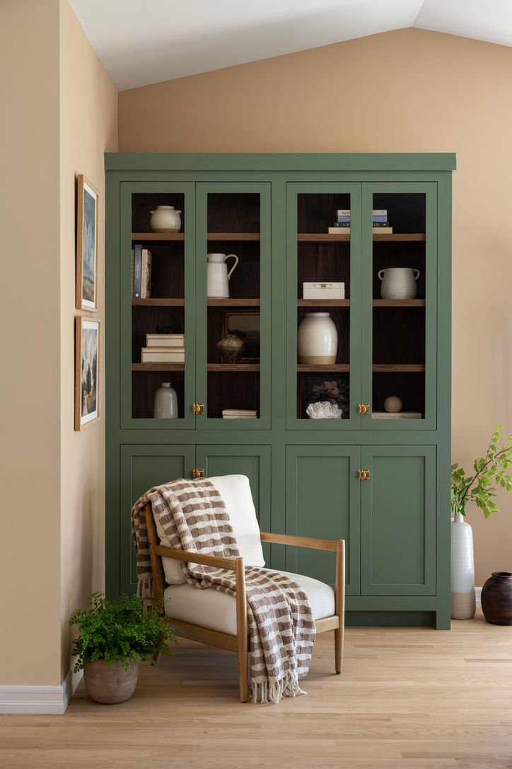 Built-in green display cabinet and striped accent chair in the Mossbank residence.