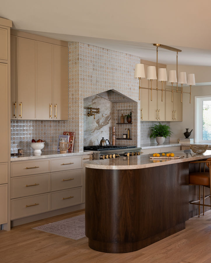 Full view of the Mossbank kitchen featuring a custom range hood, oversized island and linear pendant lighting.