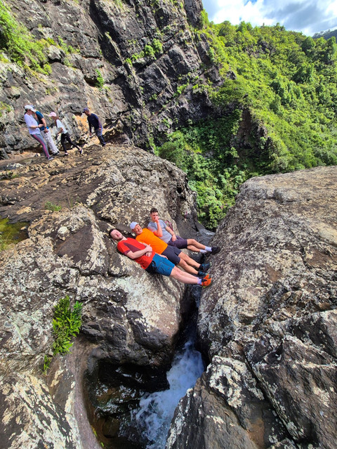 Two people relaxing on rocks by a stream