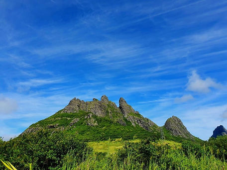 Lush green mountain peaks under a bright blue sky
