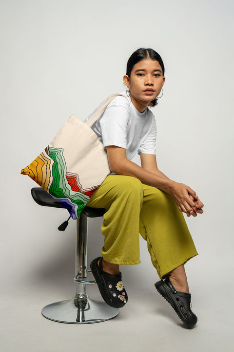 A woman sitting on a stool with a Mile High Coffee Club bag on her shoulder.