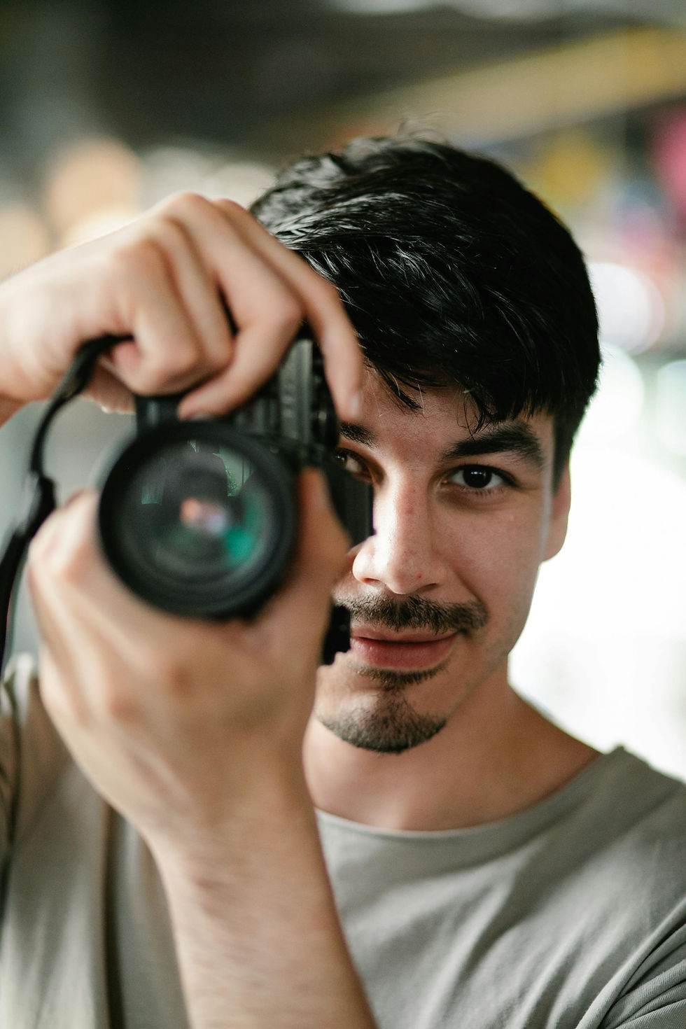 Man holding camera, looking at viewer