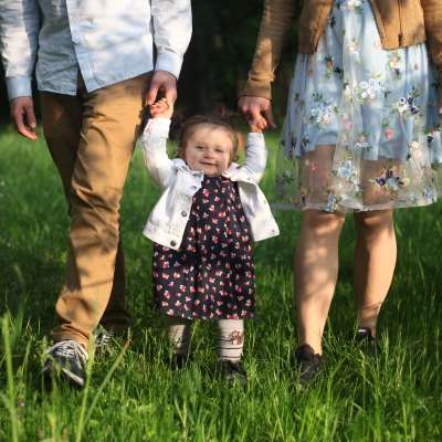 Smiling baby held by parents in grass