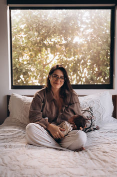 Mother sitting on a bed holding her newborn baby