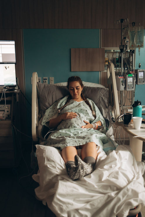Pregnant woman resting in a hospital bed during labor with medical equipment beside her