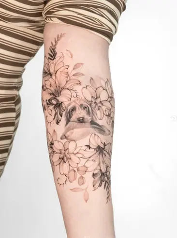 Fine line dog portrait and botanical flowers forearm tattoo by Nicolly at The Story of Us MCR, Castlefield Manchester